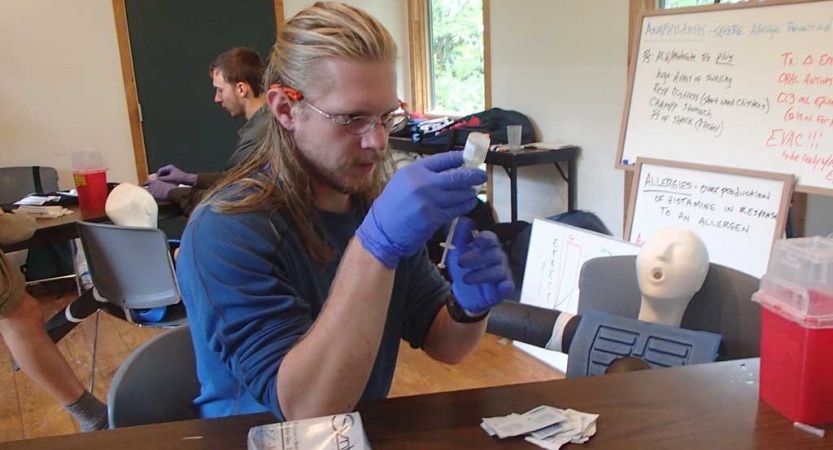 A person wearing gloves examine a vail during a wilderness first responder certification course. 